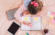 Girl sitting on bed writing in a day planner